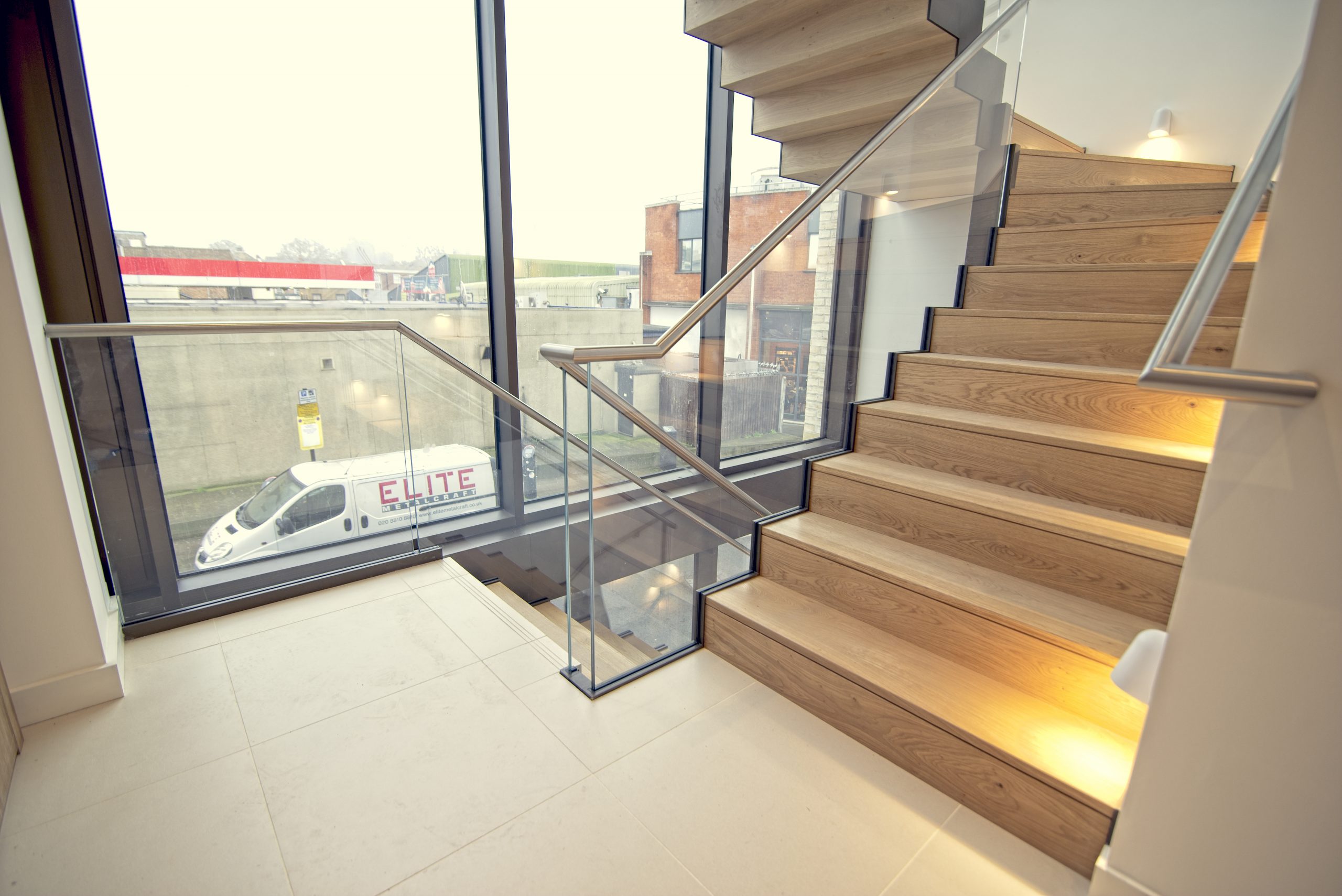 Glass staircase design with Elite Metalcraft van on road outside